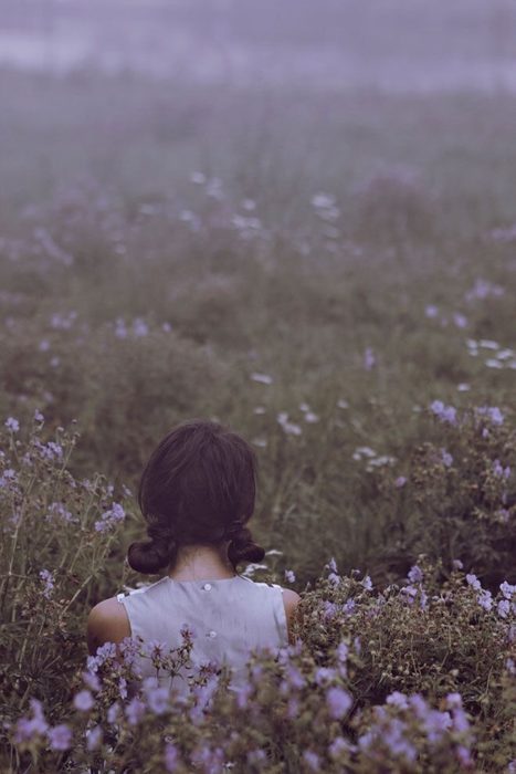 Chica con cabello corto de espladas mira un campo de lavanda