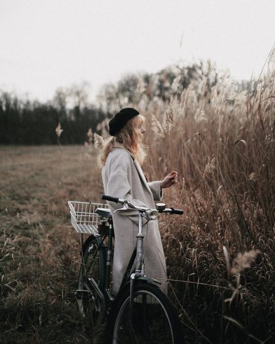 Chica con gorrito negro y una bici observa el campo