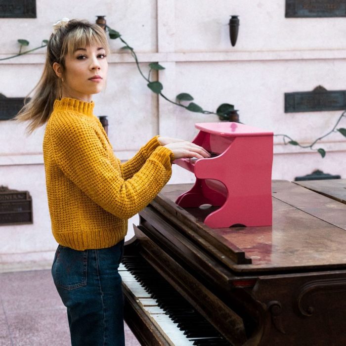 Jennette McCurdy tocando un minipiano en color rosa 