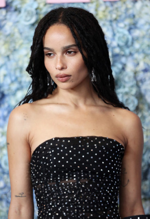 Zoë Kravitz mirando al piso, llevando un vestido estraple en negro con puntos blancos