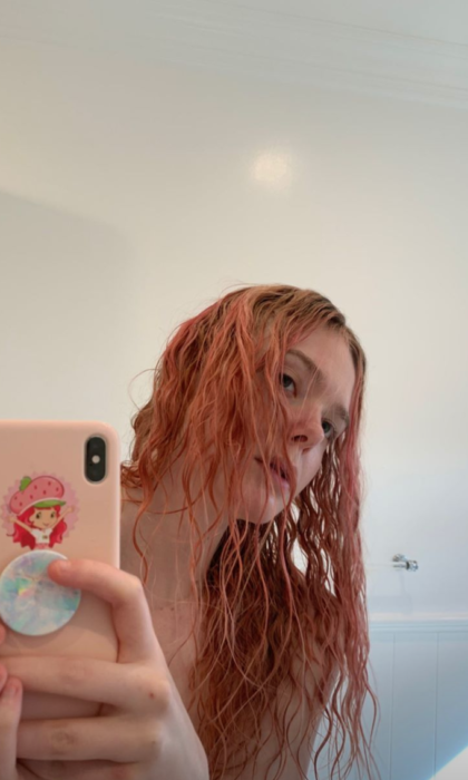 Elle Fanning tomandose una foto para mostrar su cabello de color rosa 
