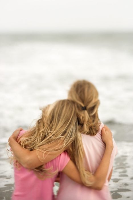 Madre e hija abrazadas mientras están mirando hacia el mar 