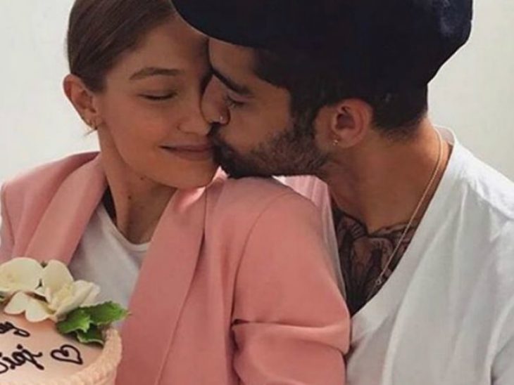 Gigi Hadid y Zayn Malik abrazados, sosteniendo un ramo de flores