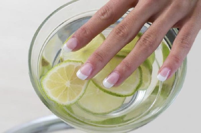 Chica metiendo sus dedos en un recipiente con agua y jugo de limón