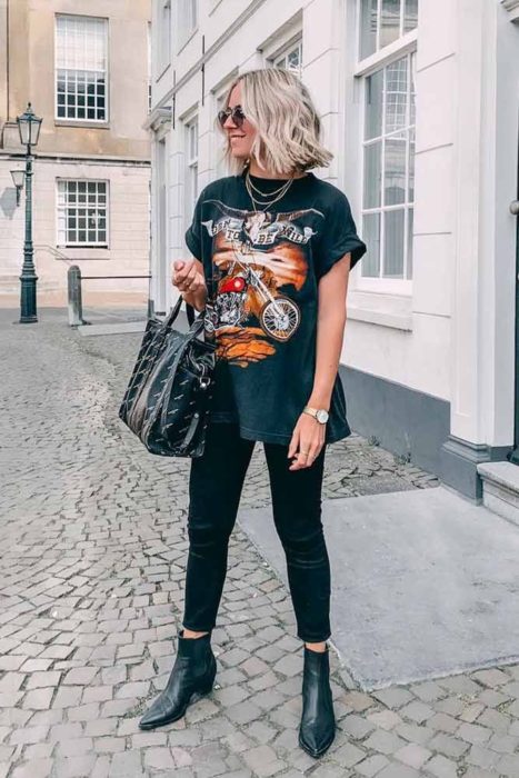 Chica usando unos skinny jeans y camiseta de rock con botines 