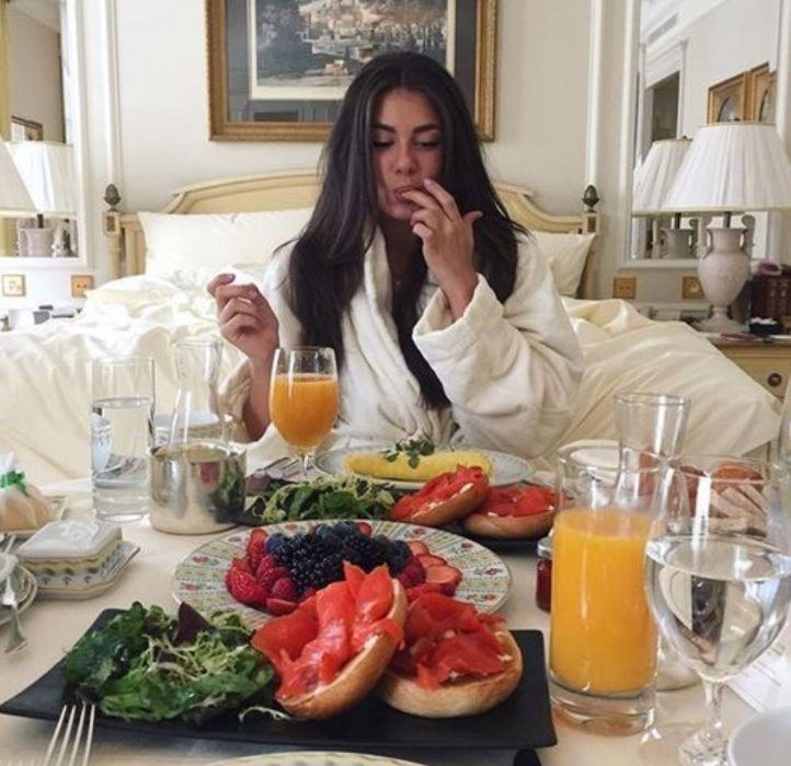 Chica tomando el desayuno en su cama 