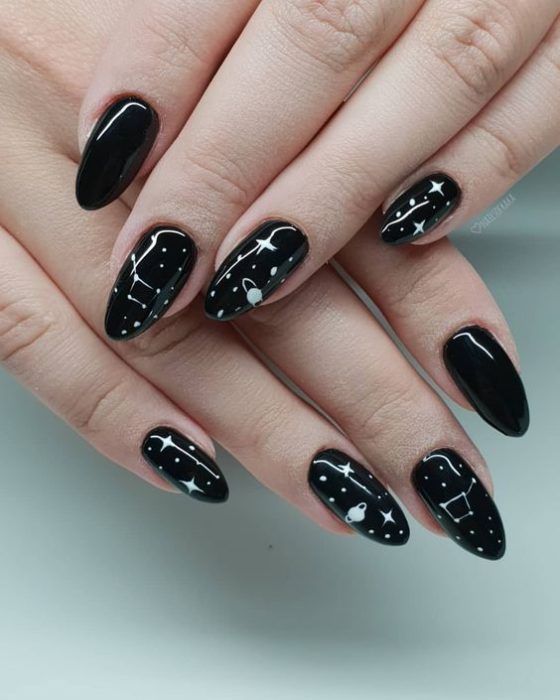 Manicura en color negro con diseño de estrellas en color blanco