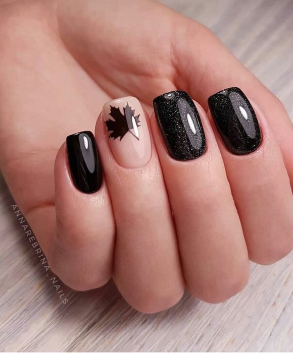 Manicura en color negro con diseño en dedo anular de una hoja de maple