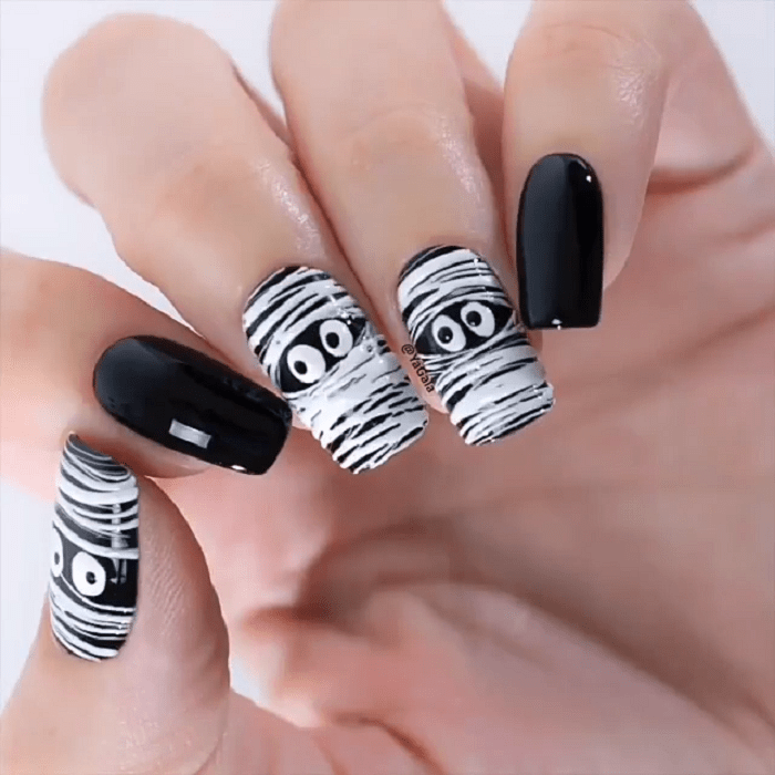 Manicura en color negro con diseño en varios dedos de momias