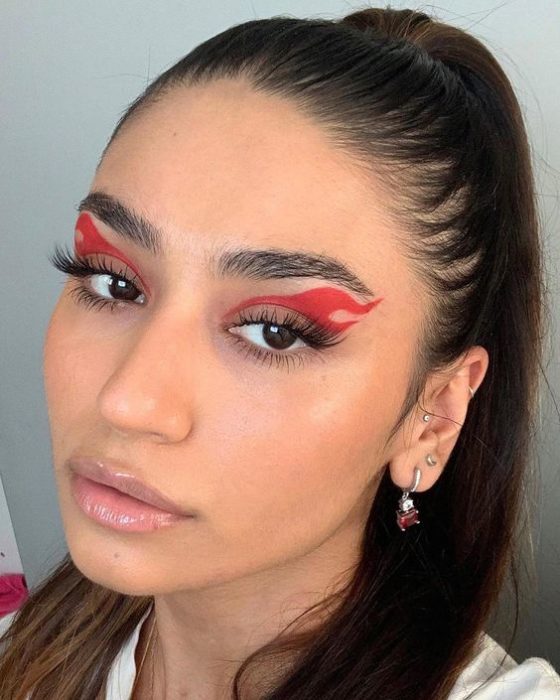 Chica morena de pelo recogido con maquillaje de flamas rojas en los rojos