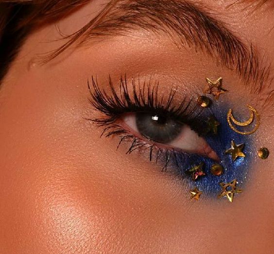 Maquillaje con sombra azul eléctrico y decoración de estrellas y luna