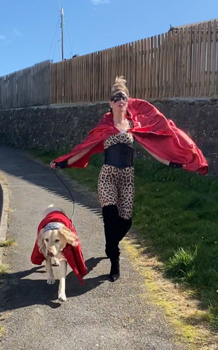 Mujer viste disfraz de superhéroe mientras paseo con su perro 