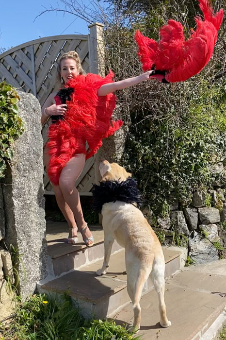 Mujer vestia de bailarina de can can mientras pasea con su perro