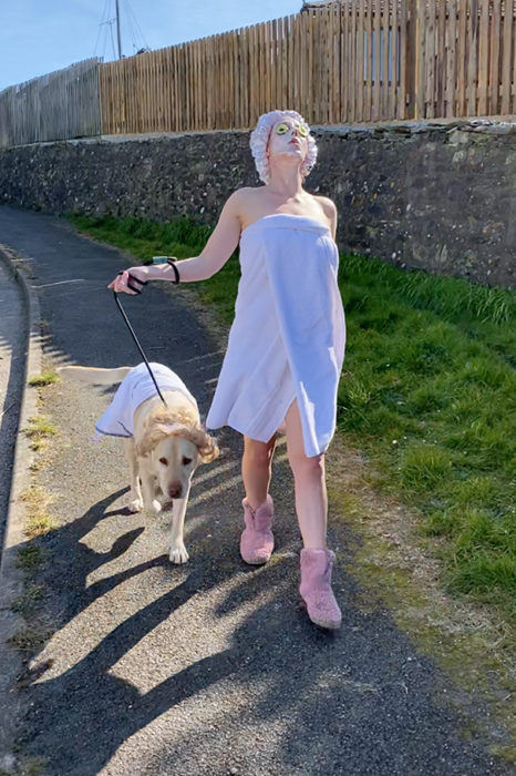 Mujer vestida con bata de baño mientras pasea con su perro