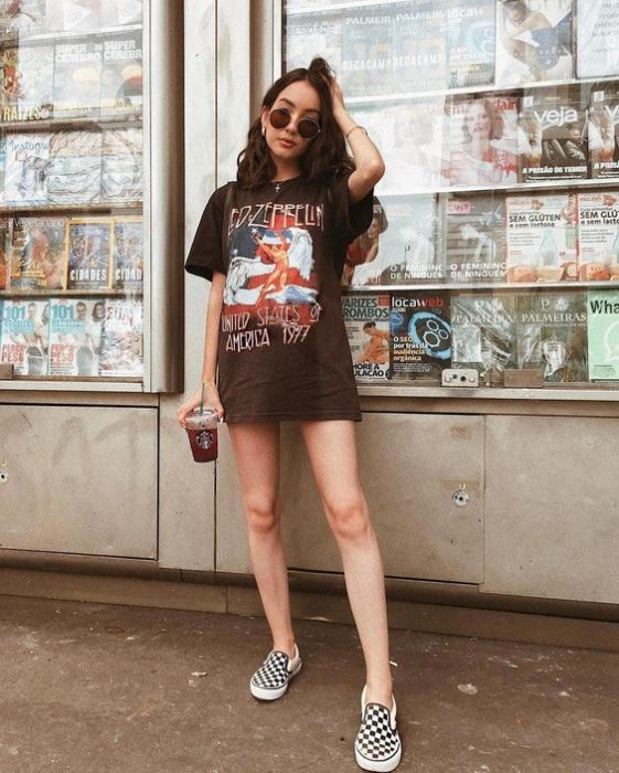 Chica con look grunge con blusa negra y vans blancos con negro de cuadros