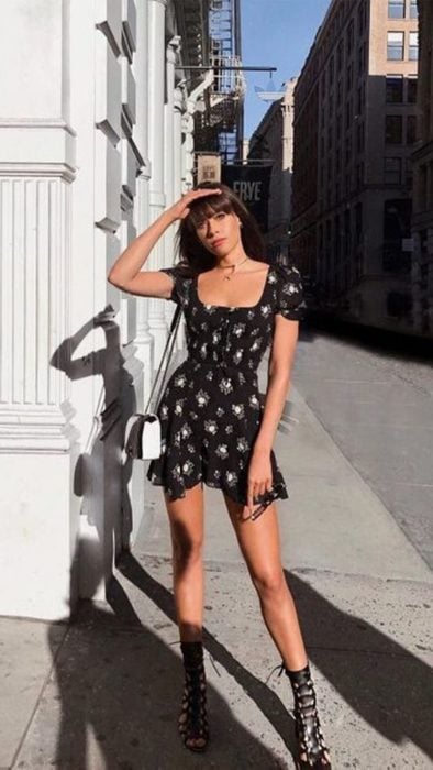 Chica cubriéndose de sol con una mano usa vestido de flores color negro