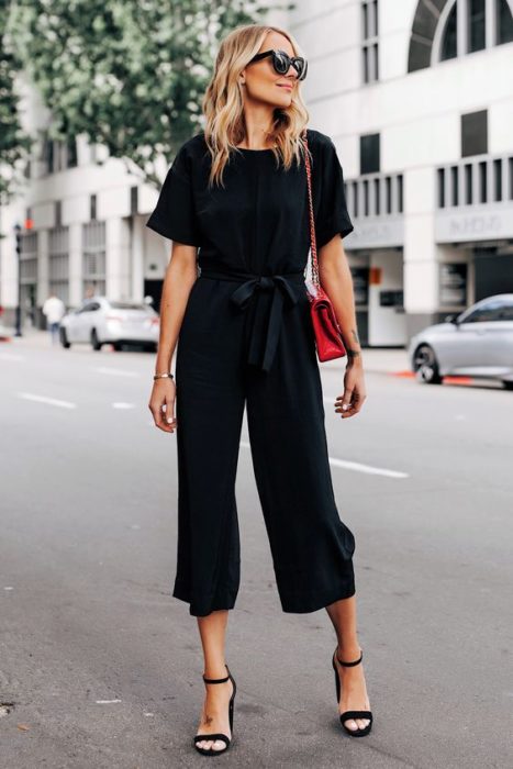 Chica rubia con total look negro y bolso rojo