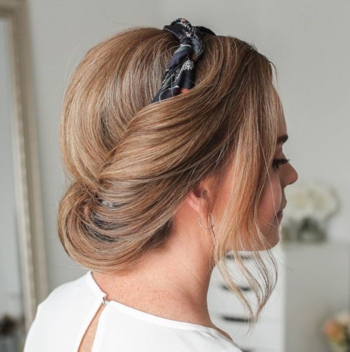 Chica con el cabello corto sujetado con una diadema en un chongo bajo 