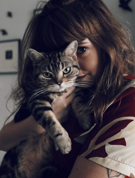 Mujer cargando a gato rayado de ojos verdes