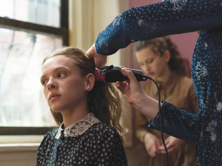 Escena de la serie Poco ortodoxa, Esty cortando su cabello a a rapa para llevar peluca