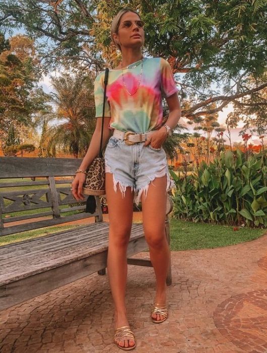 Mujer rubia y bronceada usa shorts y una playera con efecto tie dye