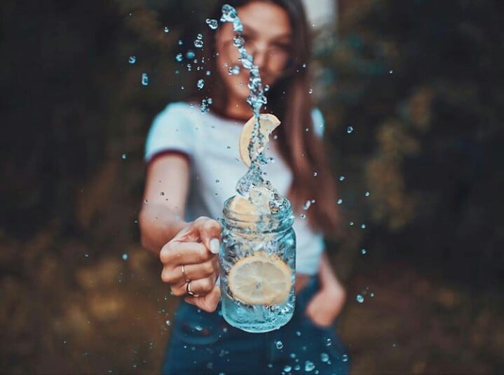 Chica sosteniendo un vaso de agua con rodajas de limón