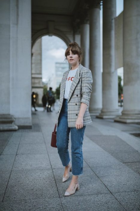 Mujer con saco café de cuadros viste jeans y zapatos beige con tacón cuadrado