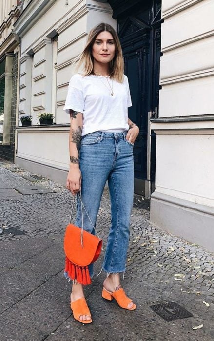 Mujer viste blusa blanca, jeans y bolsa y zapatos naranjas con tacón cuadrado