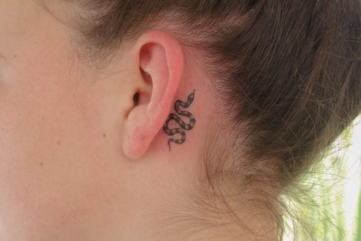Tatuaje detrás de la oreja de una serpiente