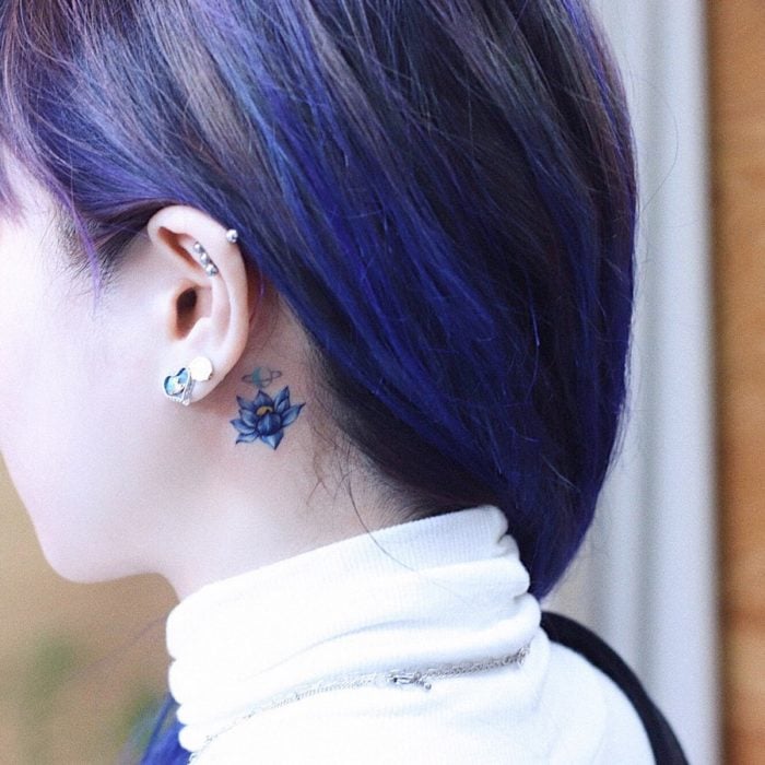 Tatuaje detrás de la oreja de una flor azul