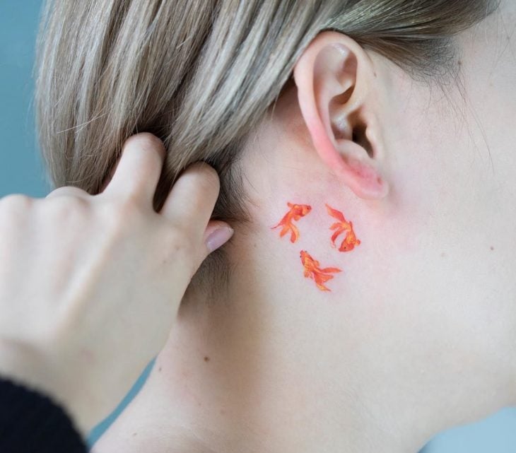 Chica con un tatuaje en forma de peces que forman un circulo 