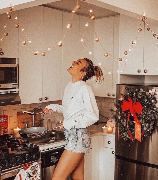 Chica con shorts cortos y sudadera blanca cocinando alegremente