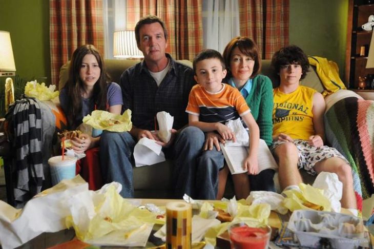 Elenco de la serie de Fox, The Middle sentados en un sillón frente a una mesa con frituras