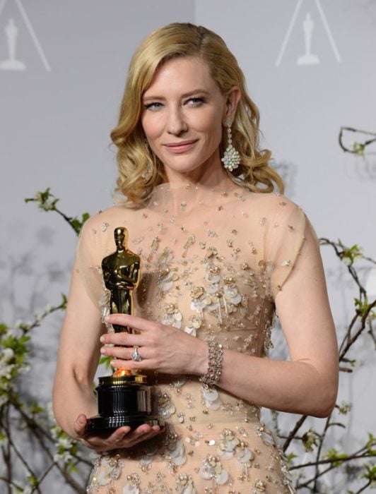 Cate Blanchett llevando u vestido dorado con transparencias sosteniendo una estatuilla al óscar