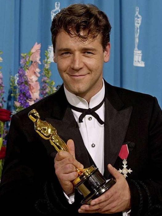 Russell Crowe con traje sastre negro sosteniendo una estatuilla de los premios óscar