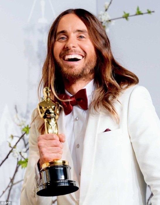 Jared Leto con saco blanco, sosteniendo una estatuilla de los premios Óscar
