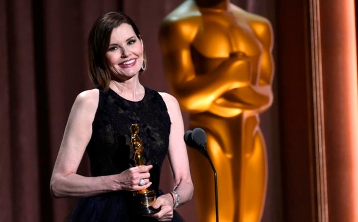Geena Davis frente a un microfono con vestido negro sosteniendo una estatuilla al Óscar