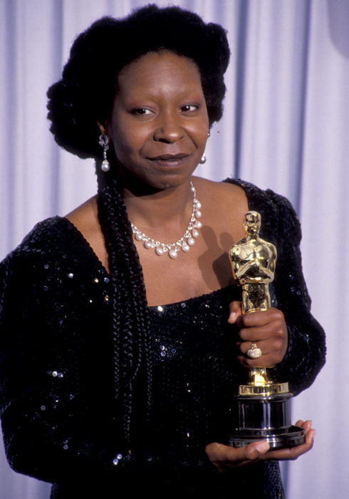 Whoopi Goldberg con vestido negro sosteniendo una estatuilla de los premios Óscar