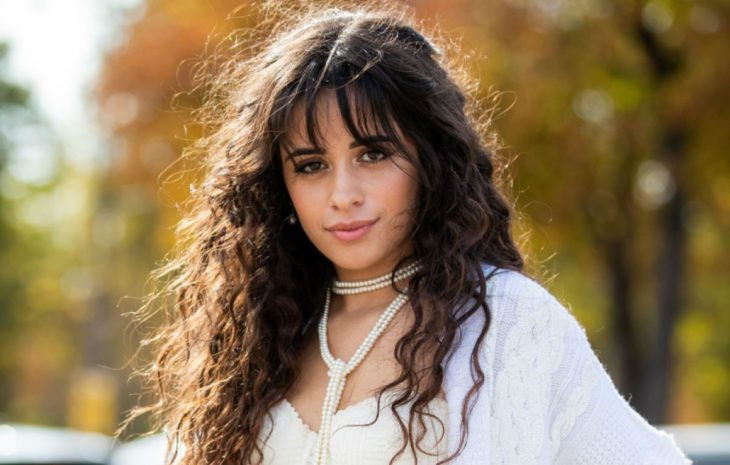 Camila Cabello sonriendo ligeramente en un jardín de flores