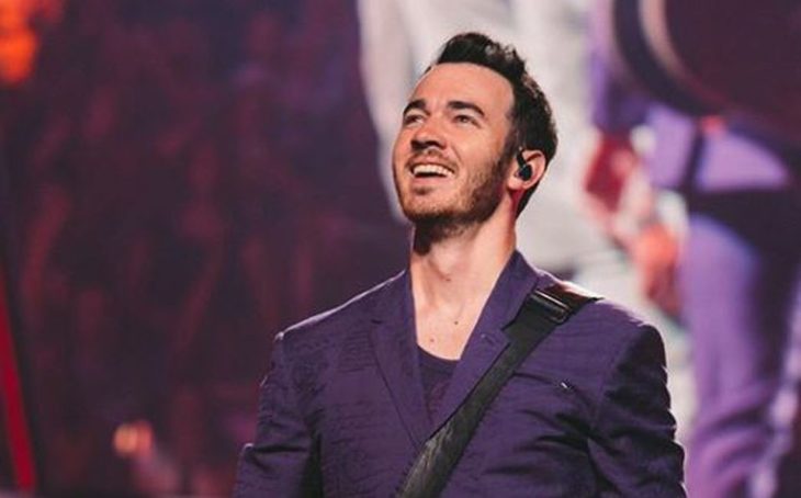 Kevin Jonas sonriendo ligeramente y mirando hacia arriba