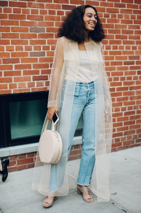 Chica usando jeans y top blnaco con un ensamble de transparencia color hueso