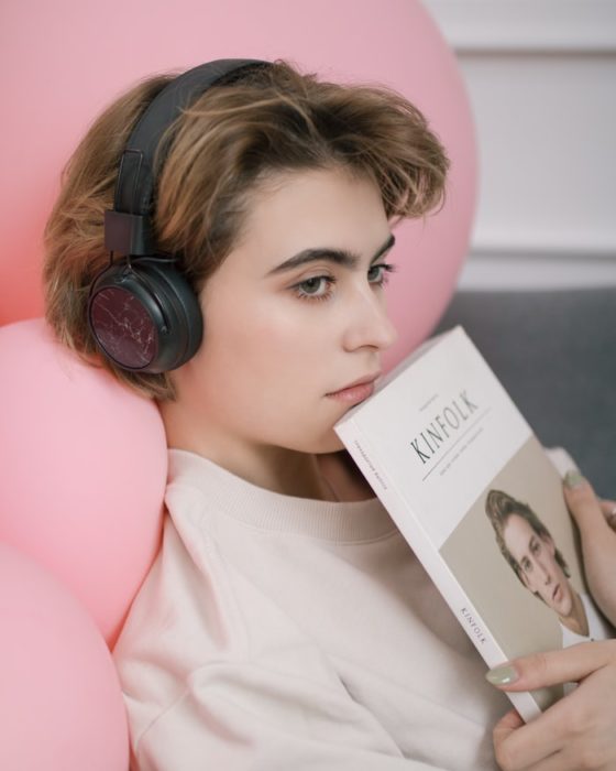 Chica escuchando música y con un libro en manos