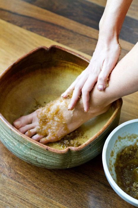 Chica exfoliando sus pies con azúcar morena