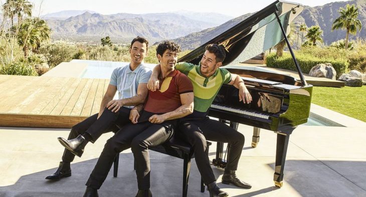 Kevin, Joe y Nick Jonas sentados en un piano al aire libre