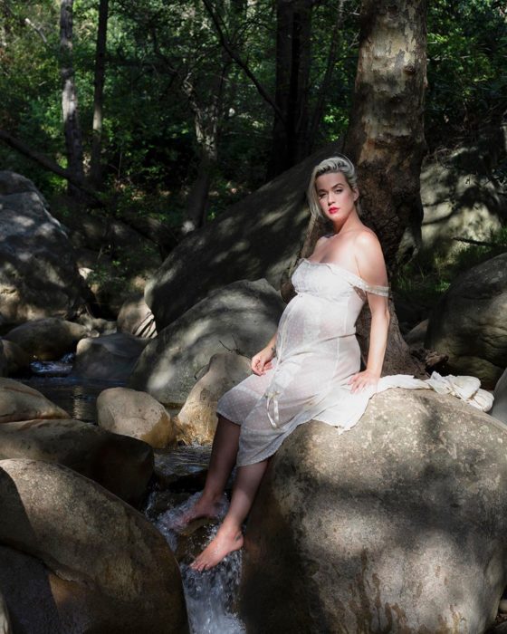 Katy Perry sentada sobre las rocas, mostrando su pancita de embarazo