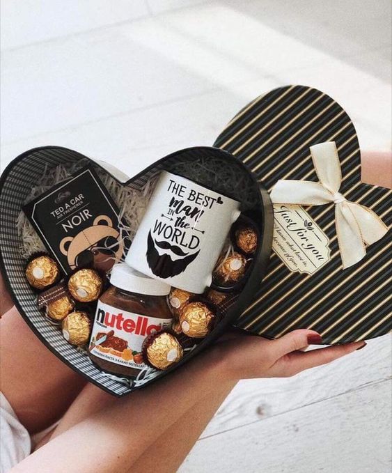 Caja en forma de corazón rellena de chocolates, nutella y una taza blanca