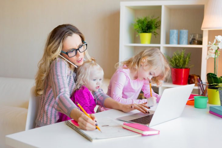 Mamá realizando trabajo en casa junto con sus hijos 