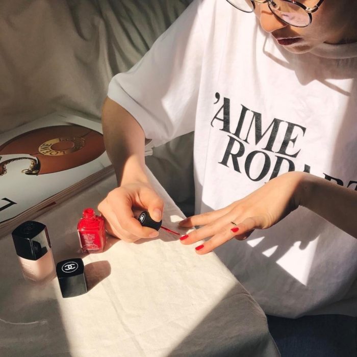 Chica pintando sus uñas en color rojo