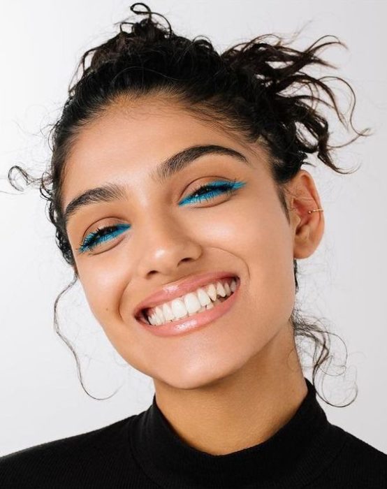 Chica morena con cabello agarrado en un chongo con delineado azul en los ojos