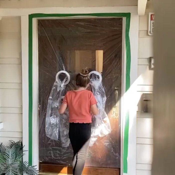 Niña abrazando a sus abuelos a través de una puerta de plástico 